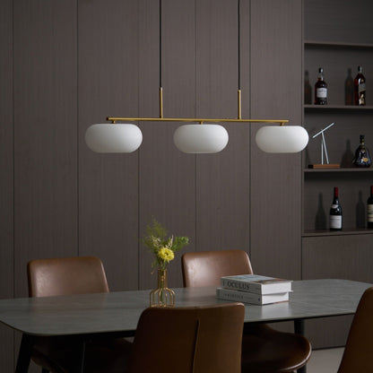 Gold-finish linear glass pendant above a dining table