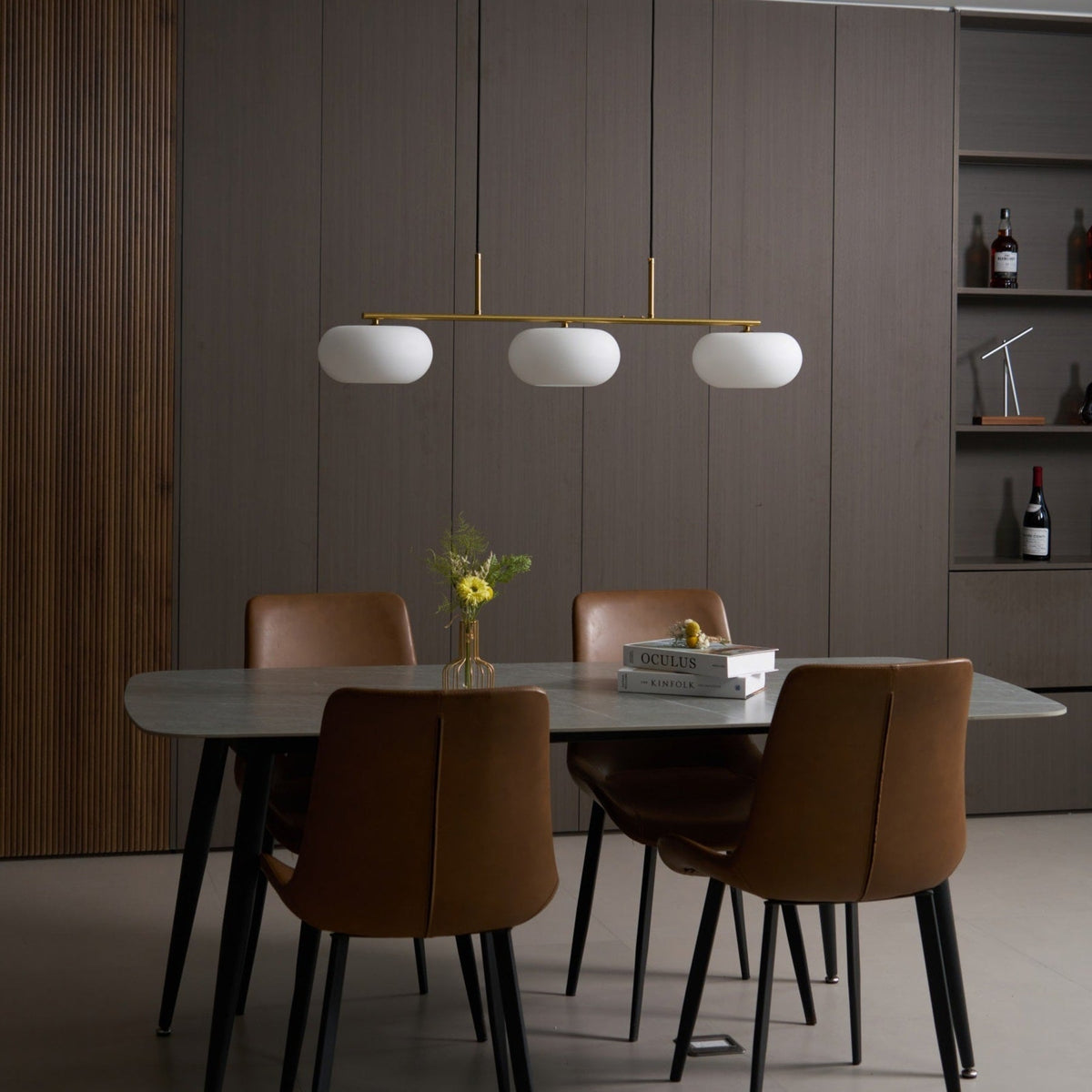 Gold-finish linear glass pendant above a dining table