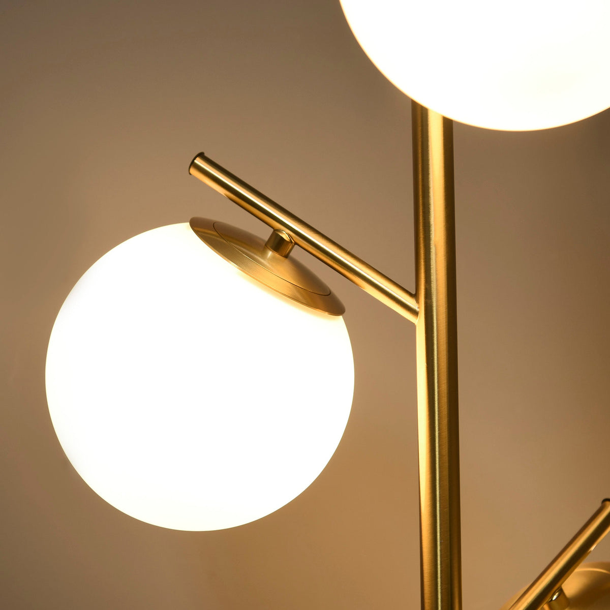 Gold tone three-light tree floor lamp with glass globe shades — close-up of shade and metal arm