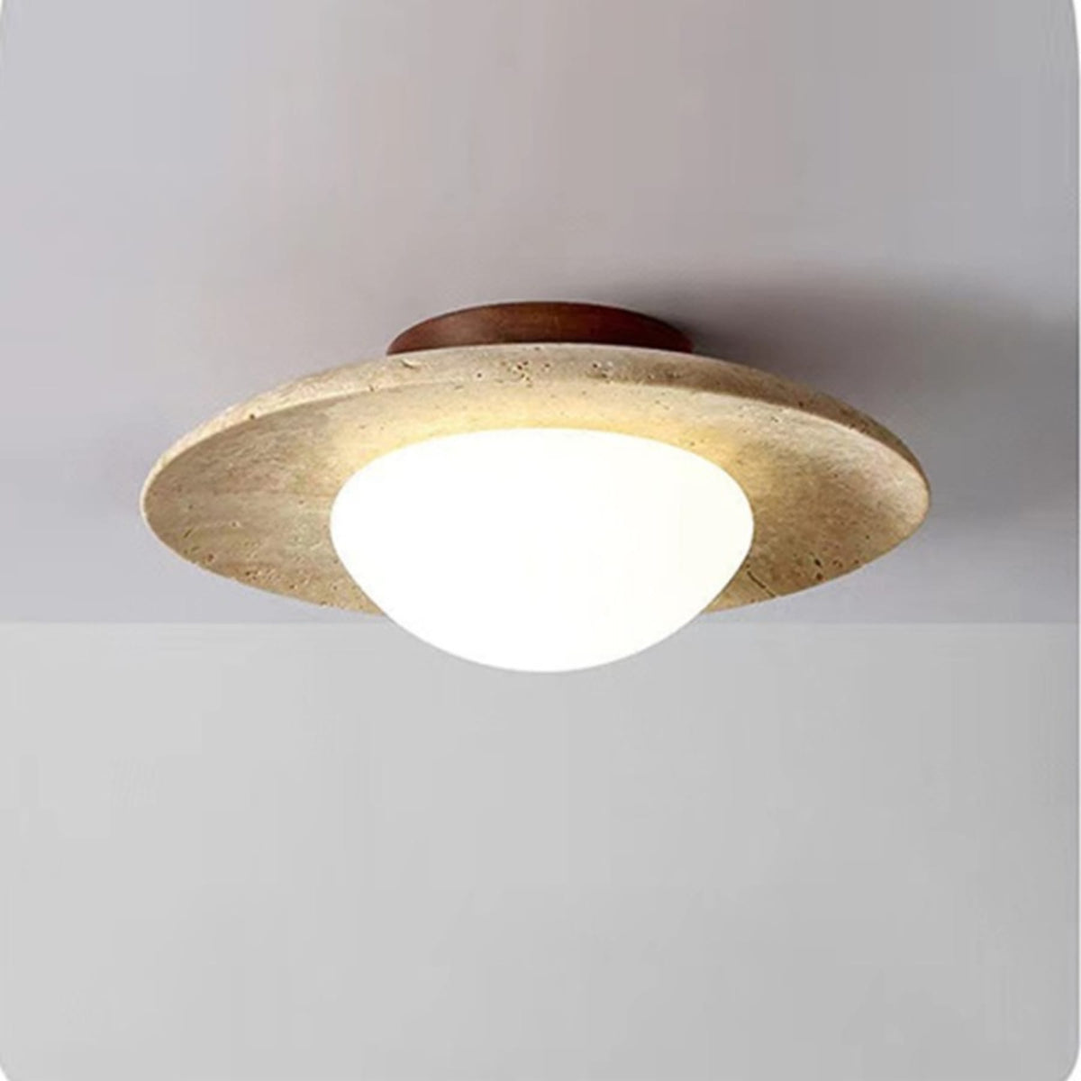 Travertine saucer ceiling light illuminated