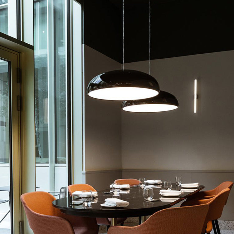 Black wide dome pendants illuminating a dining table