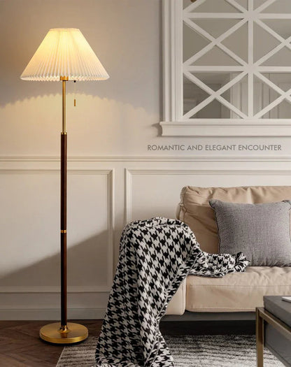 Wood-grain floor lamp with pleated shade beside a sofa