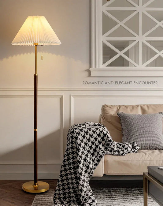 Wood-grain floor lamp with pleated shade beside a sofa