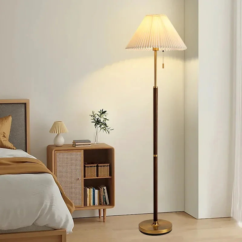 Pleated shade floor lamp beside a bed