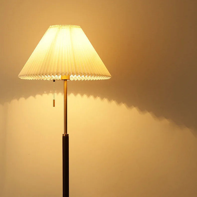 Illuminated pleated floor lamp shade casting warm light